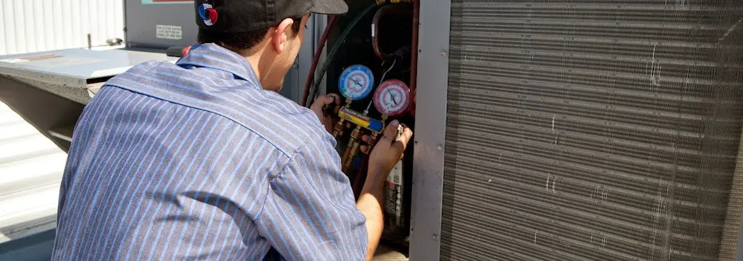 HVAC technician servicing a condenser unit in Elsmere